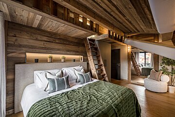 A bedroom with a ladder leading up to a loft