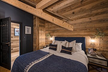 A bedroom with wood paneling and a bed with a blue blanket
