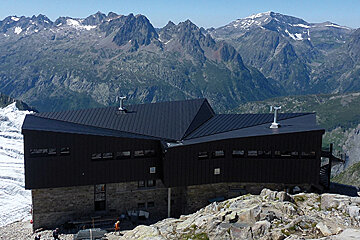 a mountain hut with a black slanted roof