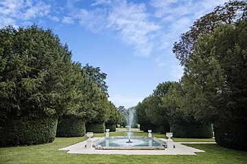A fountain in the middle of a park surrounded by trees