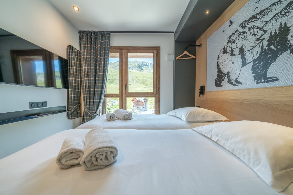 A bedroom with two beds and a bear painting on the wall