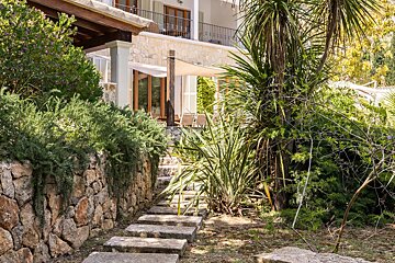 A stone walkway leads to a house with a balcony