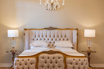 A bedroom with a bed and two lamps and a chandelier