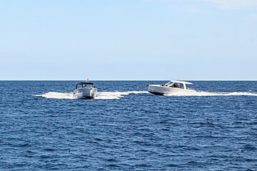 Two boats are racing in the ocean and one has a flag on the side