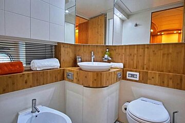 A bathroom on a boat with a sink , toilet and mirror