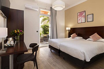 A hotel room with two beds and a desk with a picture on the wall that says happy new year