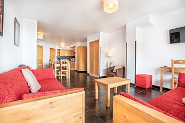 A living room with a red couch and a brown chair