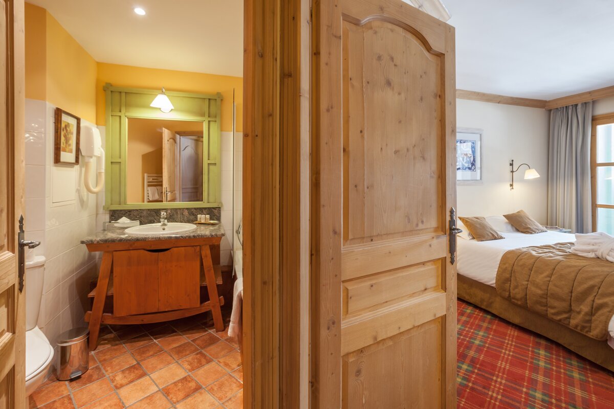 A bathroom with a sink and a mirror next to a bed