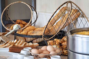 A basket of bread sits next to a basket of eggs