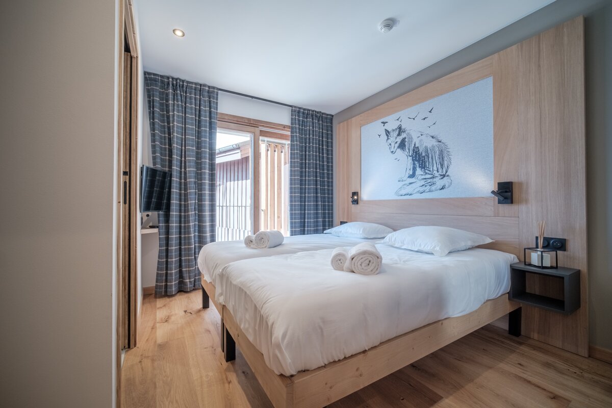 A hotel room with two beds and a picture of a wolf on the wall