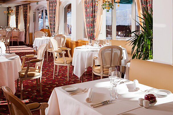A dining room with tables and chairs set for a meal