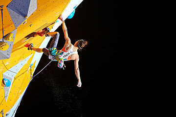 A woman climbing a wall with the word korea on her shirt
