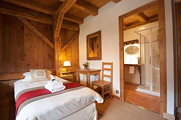 A bedroom with a single bed and a chair