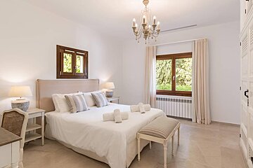 A bedroom with a large bed and a chandelier