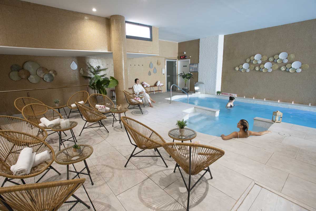 A woman sits in a chair near a swimming pool