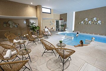 A woman sits in a chair near a swimming pool