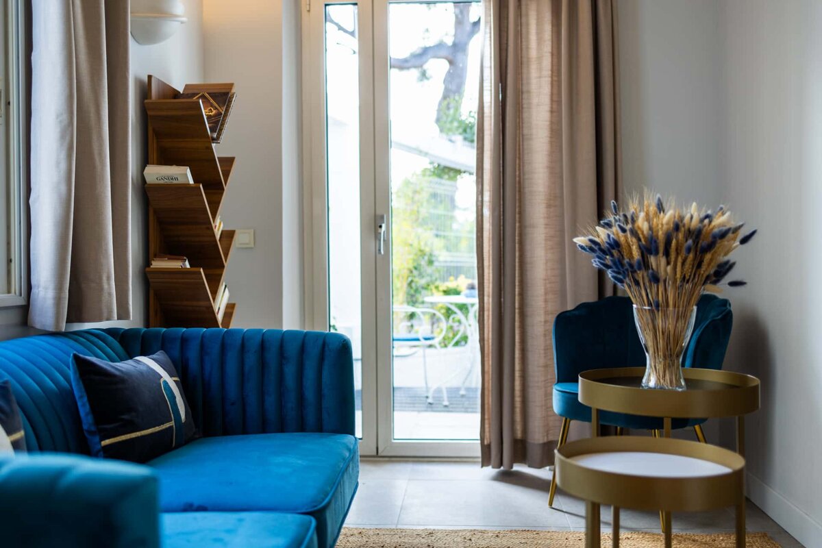 A blue couch sits in a living room next to a bookshelf with a book called cocoa on it