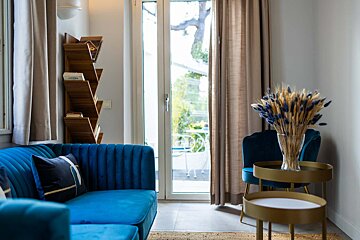 A blue couch sits in a living room next to a bookshelf with a book called cocoa on it