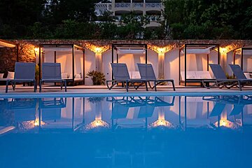 A row of lounge chairs are lined up next to a swimming pool