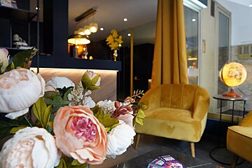 A vase of flowers sits on a table in front of a yellow chair