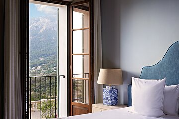 A bedroom with a blue headboard and a lamp