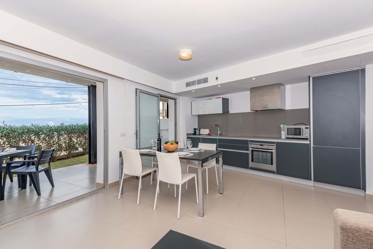 A kitchen with a table and chairs and a bowl of fruit