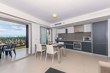 A kitchen with a table and chairs and a bowl of fruit