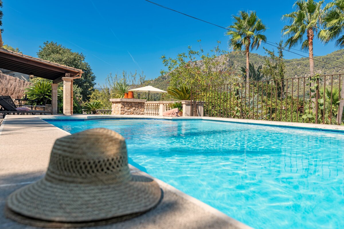 A straw hat sits on the edge of a swimming pool