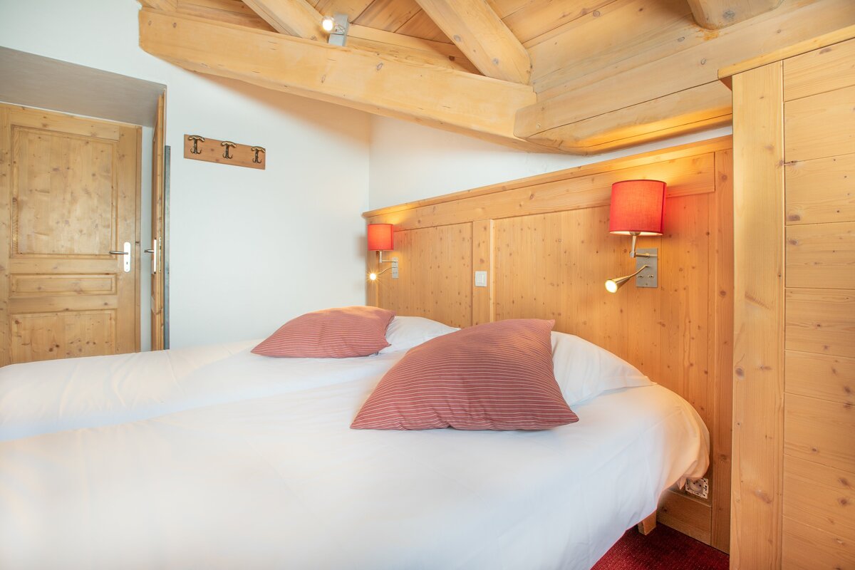 A bedroom with two beds and a wooden headboard