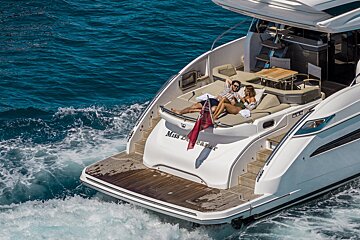 A couple relaxes on the aft deck of a white yacht named