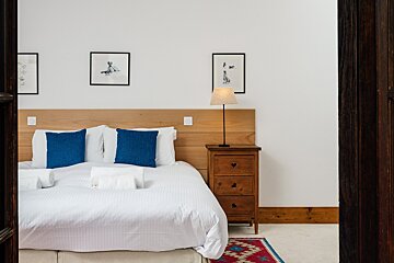 A bedroom with white sheets and blue pillows