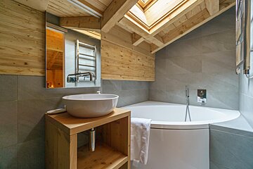 A bathroom with a tub and a sink under a skylight