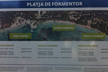 a sign at the beach noting areas where parasols are more expensive