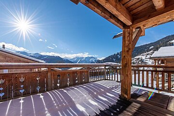 A balcony with a view of snowy mountains on a sunny day