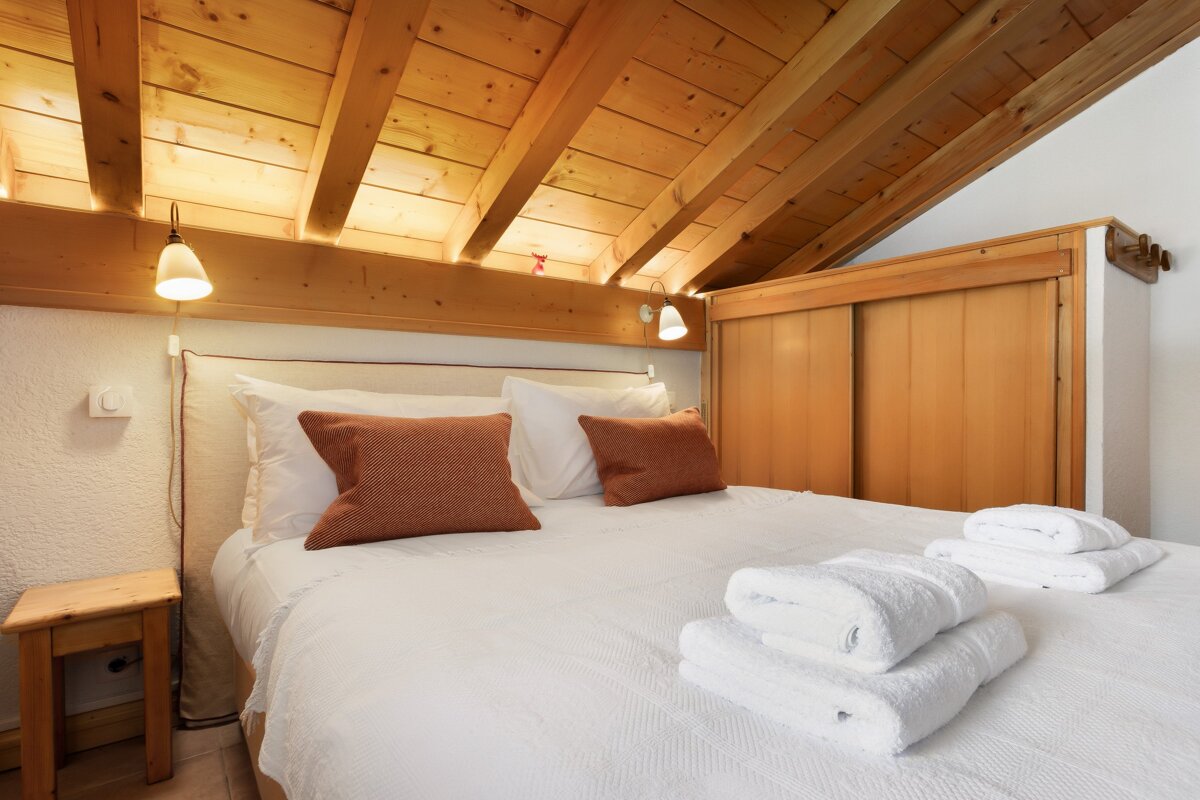 A bedroom with a wooden ceiling and a bed