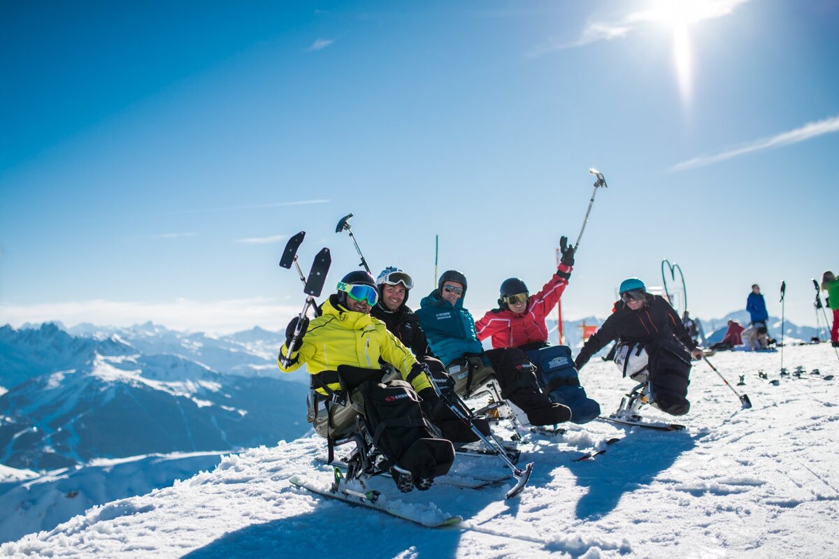A group of skiers are sitting on top of a snow covered mountain