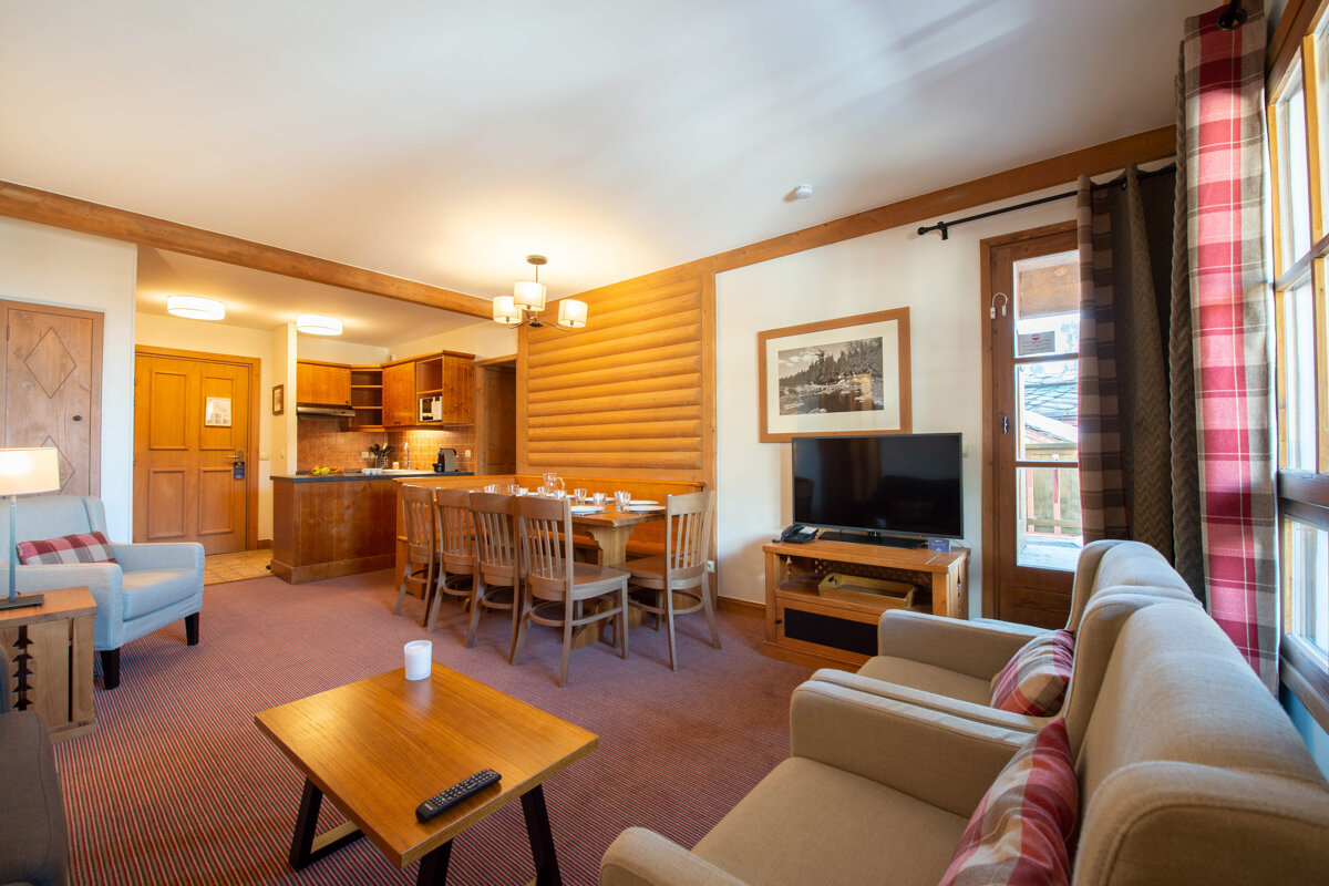 A living room with a table and chairs and a flat screen tv