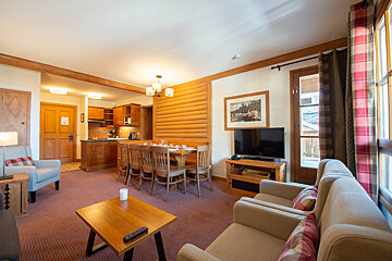 A living room with a table and chairs and a flat screen tv