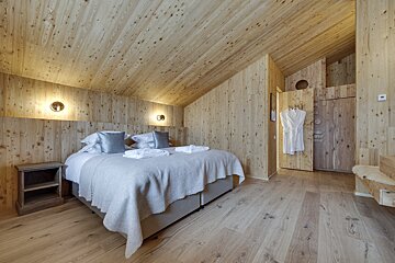 A bedroom with a wooden ceiling and two beds
