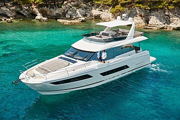 A white yacht is floating in the water near a rocky shoreline