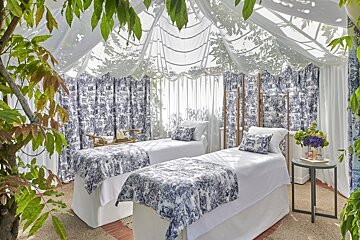 Two beds under a white tent with blue and white curtains