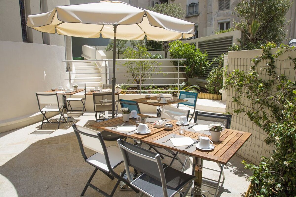 A patio with tables and chairs under an umbrella