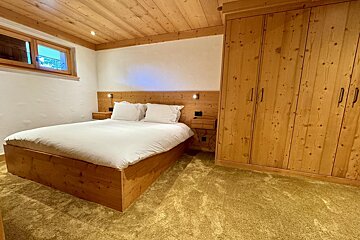 A bedroom with a wooden bed and wooden cabinets