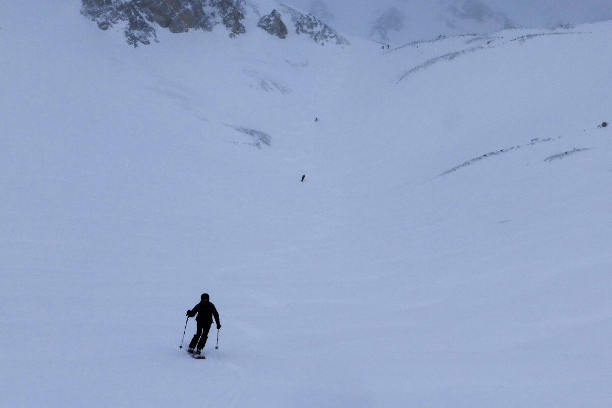 three skiers in a flat light area