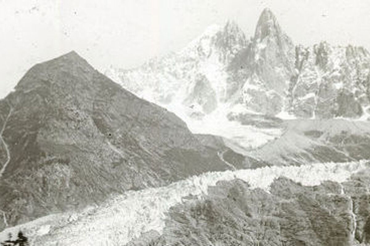 A black and white photo of a mountain range with a glacier in the foreground