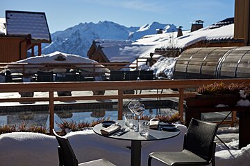 A table and chairs in the snow with mountains in the background