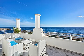 A balcony with chairs and a table overlooking the ocean