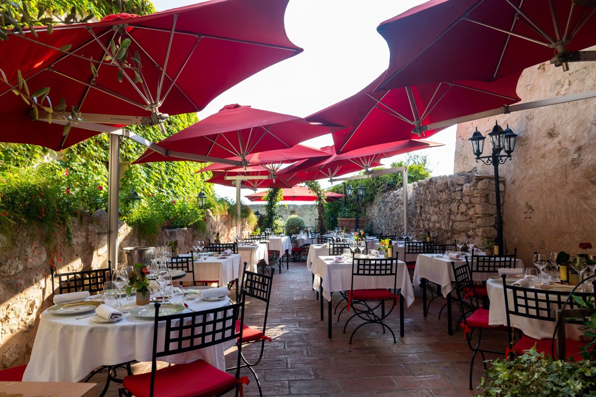 A restaurant with tables and chairs under red umbrellas