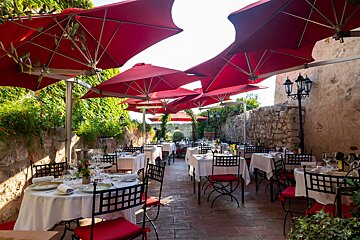 A restaurant with tables and chairs under red umbrellas