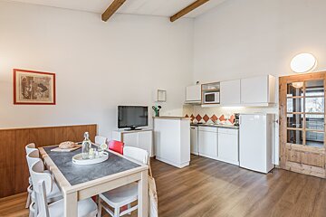 A kitchen with a table and chairs and a television